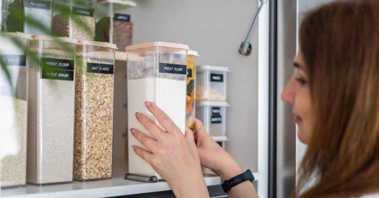 Female tidying up in cupboard or pantry in the kitchen